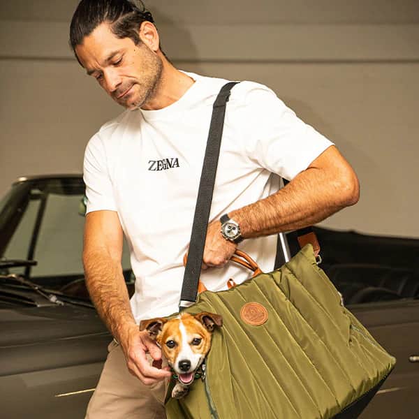 Ein Mann trägt seinen Hund in der stylischen Tragetasche Sunny